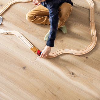 young girl on COREtec vinyl plank floor playing with a wooden train set 