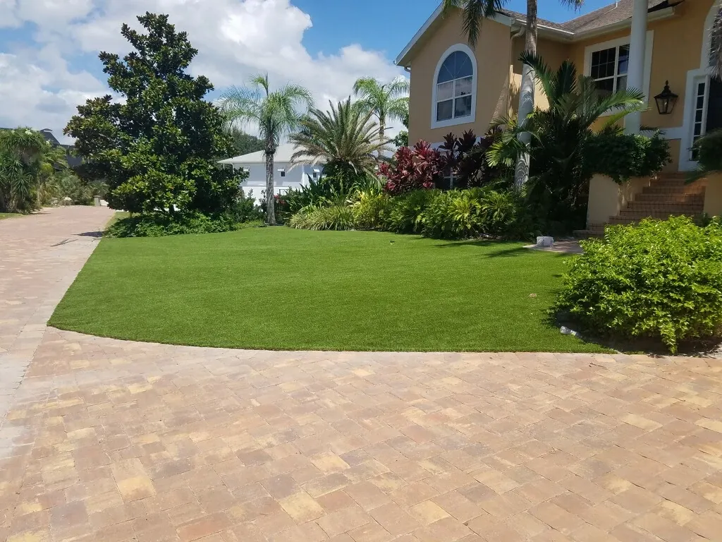 Lush green lawn with brick pathway in front of a house