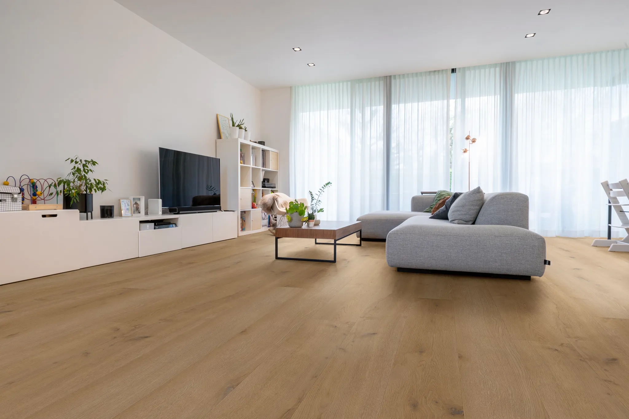 Modern living room with light wood look luxury vinyl plank flooring, large windows, and contemporary furniture