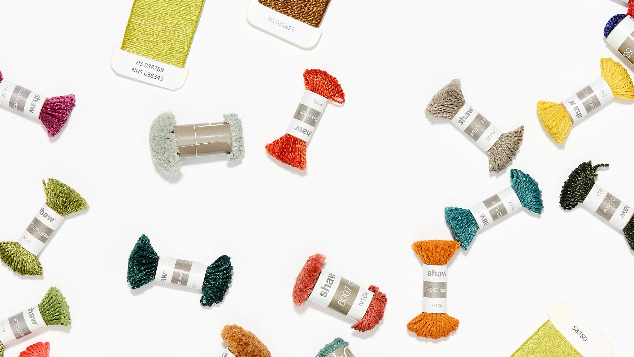 Spools of colorful yarn in various shades including red, blue, green, yellow, orange, and black arranged on a white background