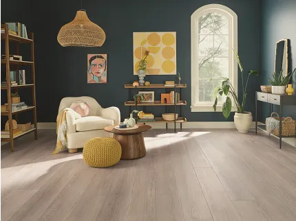 This COREtec product features Soft Step, our newest attached underlayment. living room with light wood look vinyl plank and quirky artwors with cream easy chair yellow poof ottoman and small side table