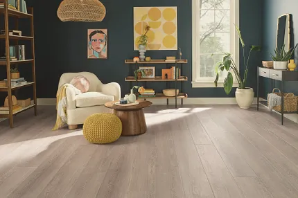 This COREtec product features Soft Step, our newest attached underlayment. living room with light wood look vinyl plank and quirky artwors with cream easy chair yellow poof ottoman and small side table