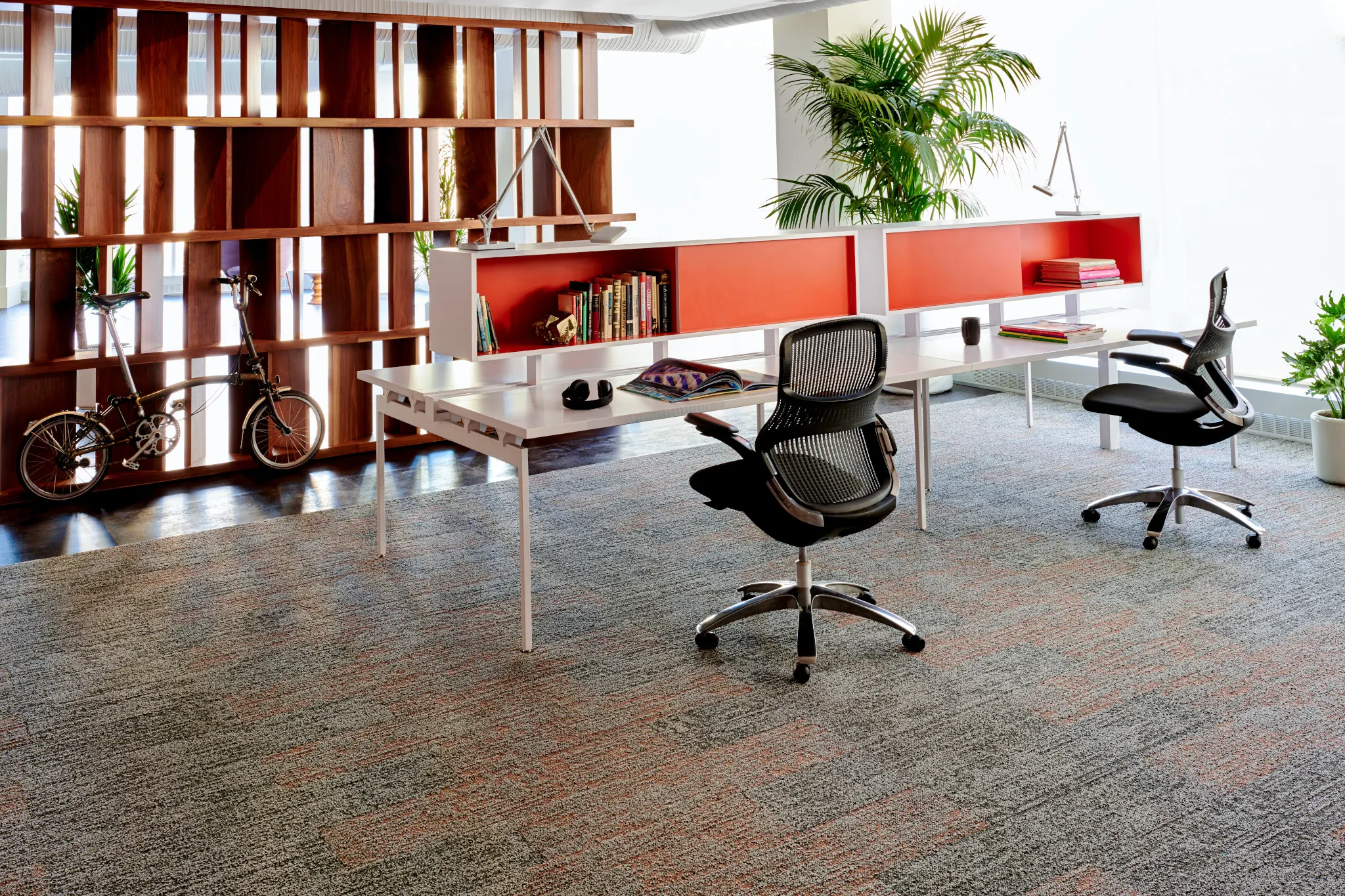 Modern office space with commercial carpet tile in shades of gray and orange, featuring ergonomic chairs and a wooden bookshelf