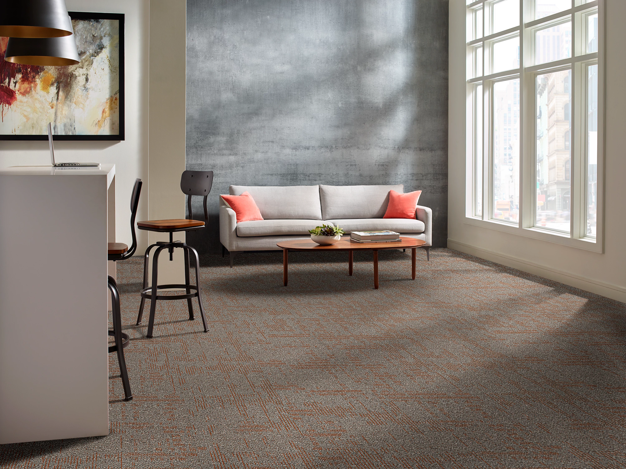 
  "Modern living room with patterned carpet flooring in shades of gray and orange, featuring a cozy sofa with coral pillows and a contemporary art piece on the wall"
)