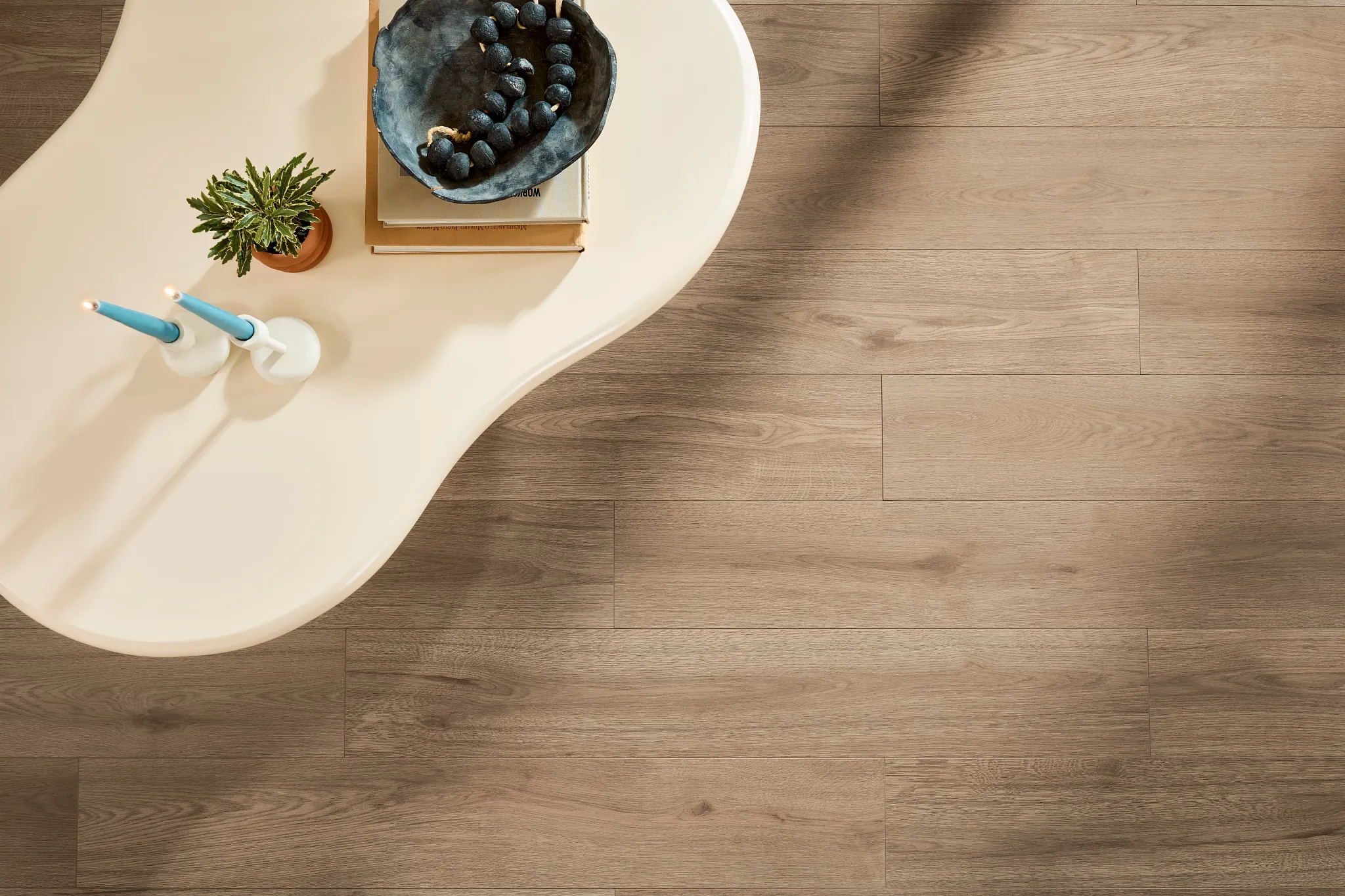 Residential resilient mineral core flooring in a warm wood tone with dimensions 47.64x7.6 inch, featuring a modern living room scene with a stylish table and decor.