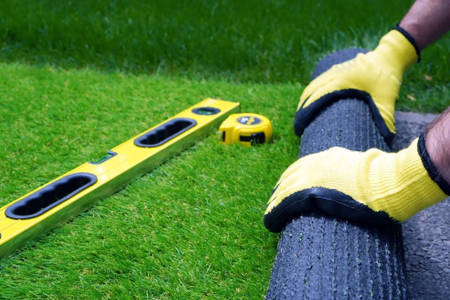 Installation of artificial grass with tools and gloves