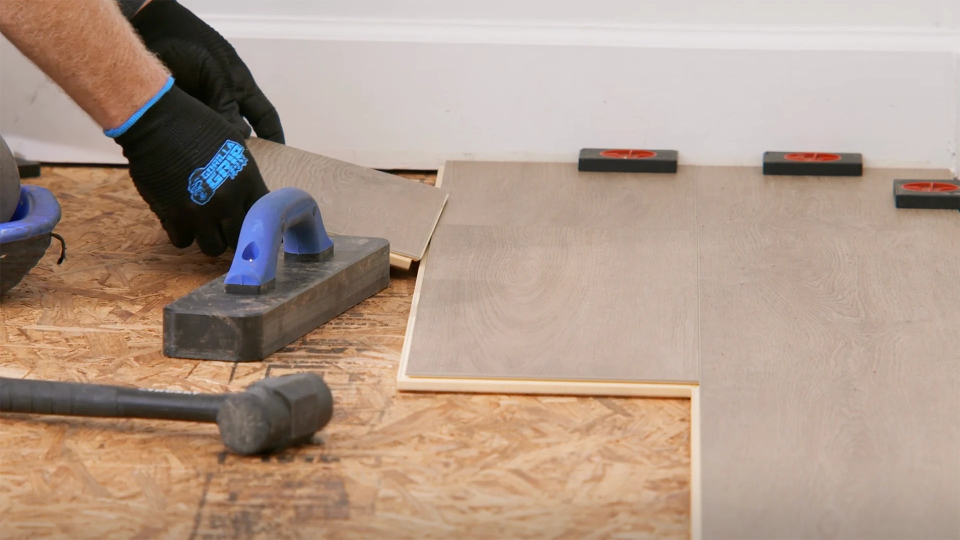 Installation of wood look luxury vinyl plank flooring with tools and spacers