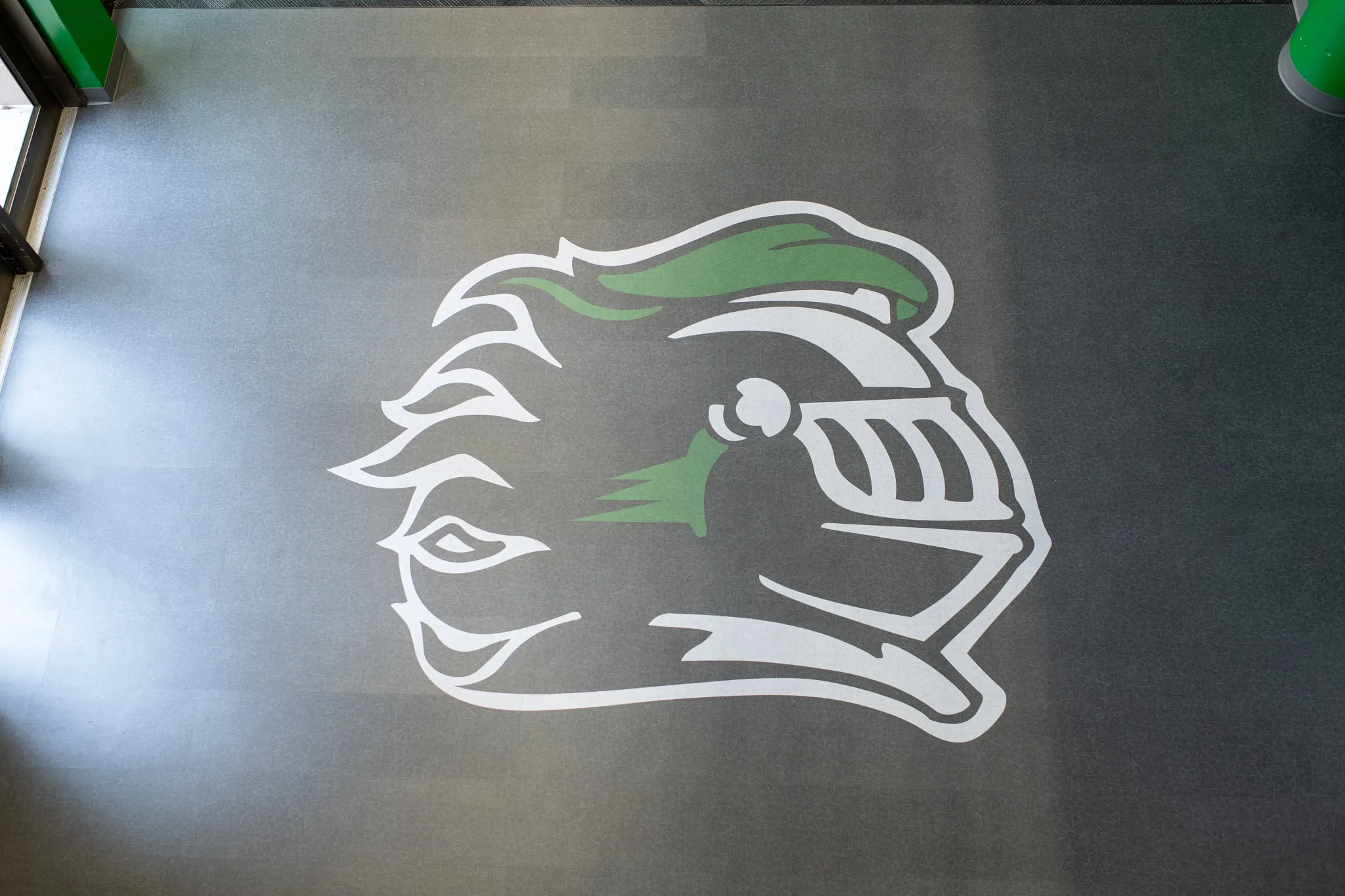 Heavy commercial luxury vinyl tile with green and white knight logo in an education facility