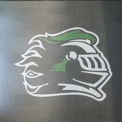 Durable LVT flooring featuring knight emblem for educational spaces Heavy commercial luxury vinyl tile with green and white knight logo in an education facility