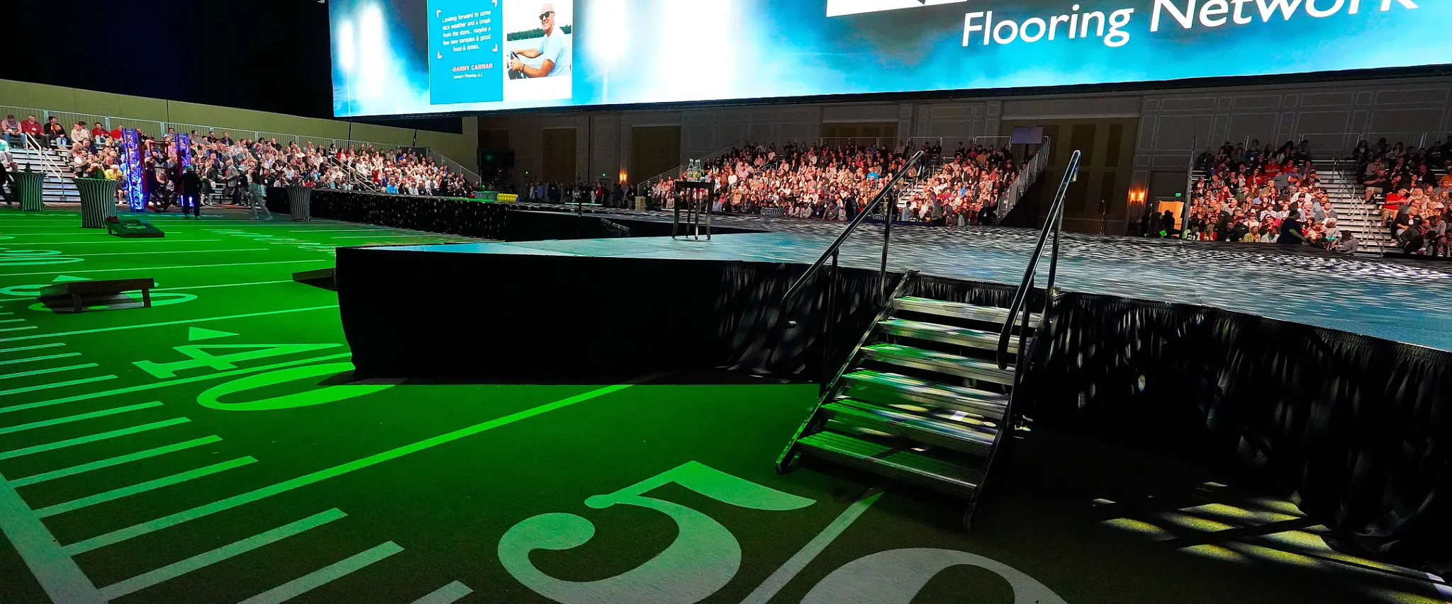 Large event stage with audience and green flooring