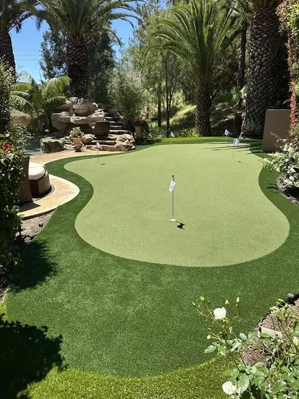 Outdoor putting green surrounded by lush landscaping