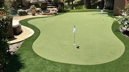 Backyard putting green with tropical scenery Outdoor putting green surrounded by lush landscaping