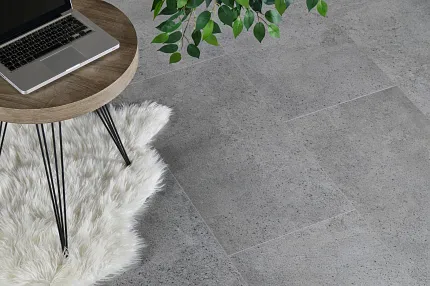 Gray Stone Look Luxury Vinyl Tile Flooring in Modern Living Room Scene living room with stone look luxury vinyl tile floor in gray with a round wooden table with a laptop and a white fluffy rug