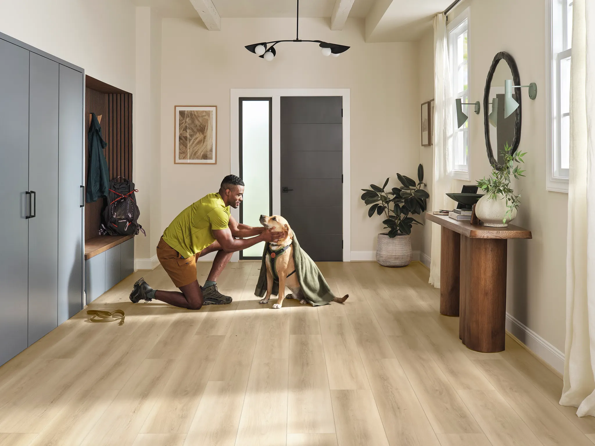 Modern entryway with a man kneeling down to dry off a golden retriever on wood look luxury vinyl plank flooring.