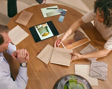 Innovative Luxury Vinyl Flooring Consultation with Swatches Two people discussing luxury vinyl flooring options with wood and fabric swatches on a table