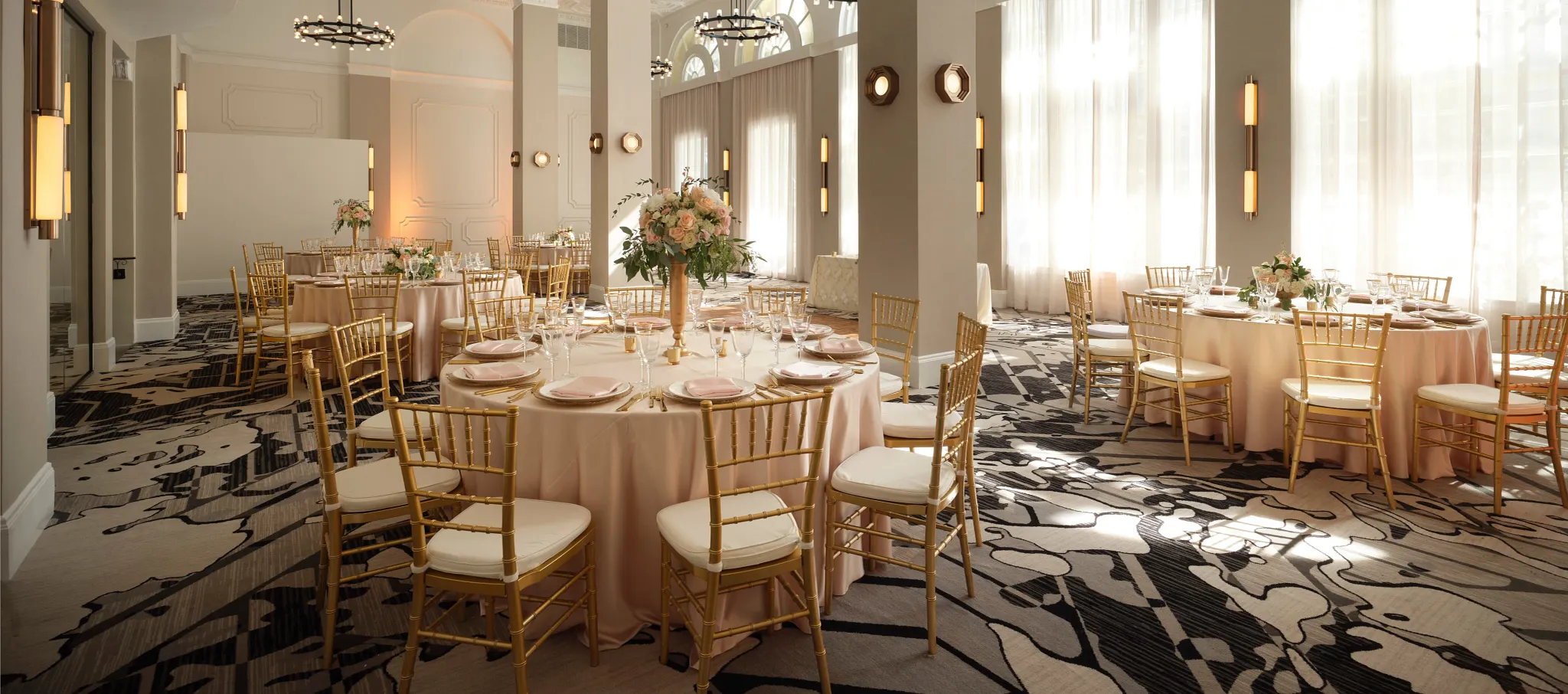 Elegant hospitality venue with round tables and gold chairs on patterned commercial carpet flooring