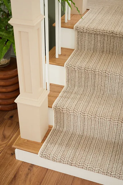 Beige and Cream Striped Carpet on Wooden Stairs - Elegant Home Flooring Design Beige and cream striped carpet on wooden staircase with green plant in background