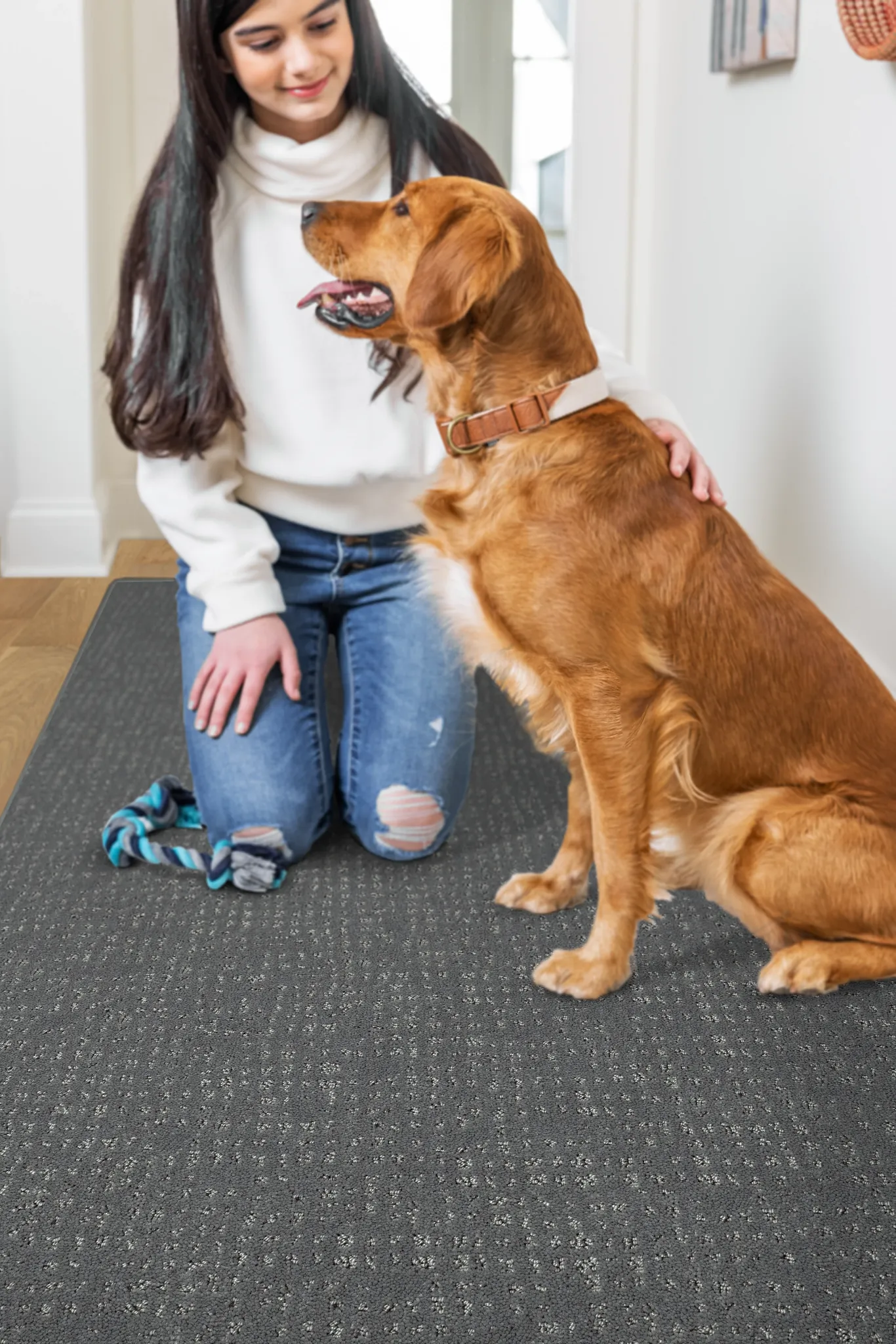 Woman kneeling on patterned carpet with a golden retriever in a cozy home setting