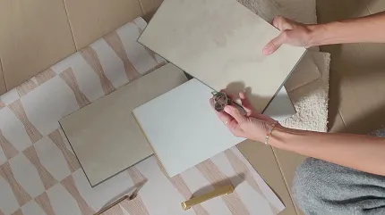 Beige and Cream Vinyl Tile Samples for Residential Flooring Person holding beige and cream vinyl tile samples on a patterned rug