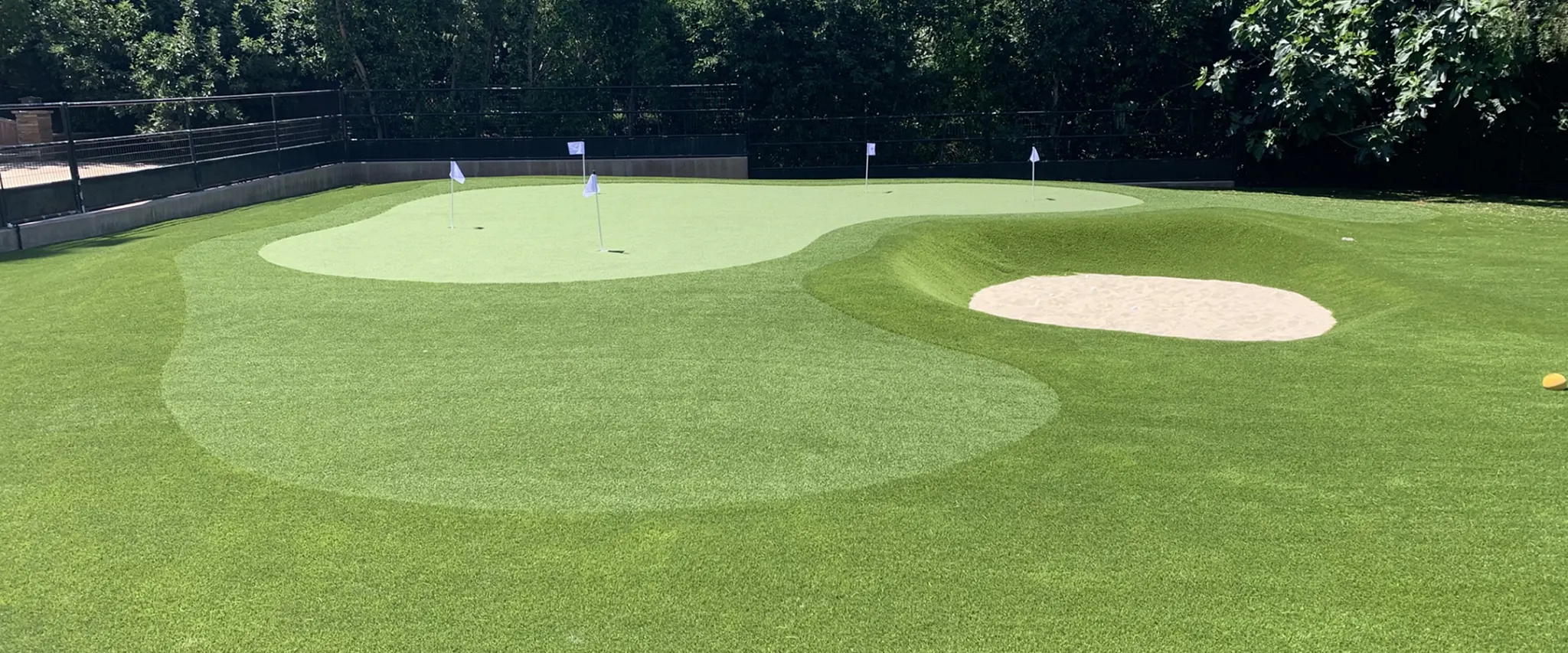 Artificial grass putting green with sand trap in outdoor setting
