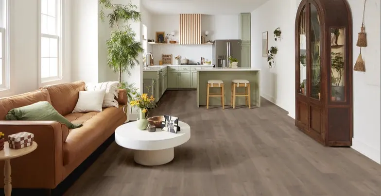 Modern living room with brown sofa and stylish kitchen featuring wood-look flooring