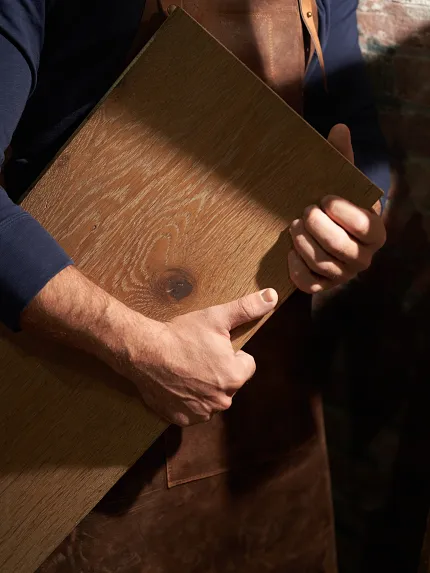 Durable Hardwood Flooring Sample - Natural Wood Grain Detail Man holding a sample of hardwood flooring with visible wood grain and natural color