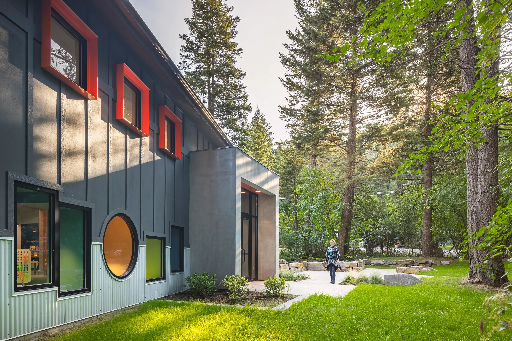 Modern educational facility exterior with colorful windows and lush greenery