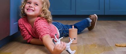 Style Tawny Beech - small girl child playing with a toy horse on floor with a spill