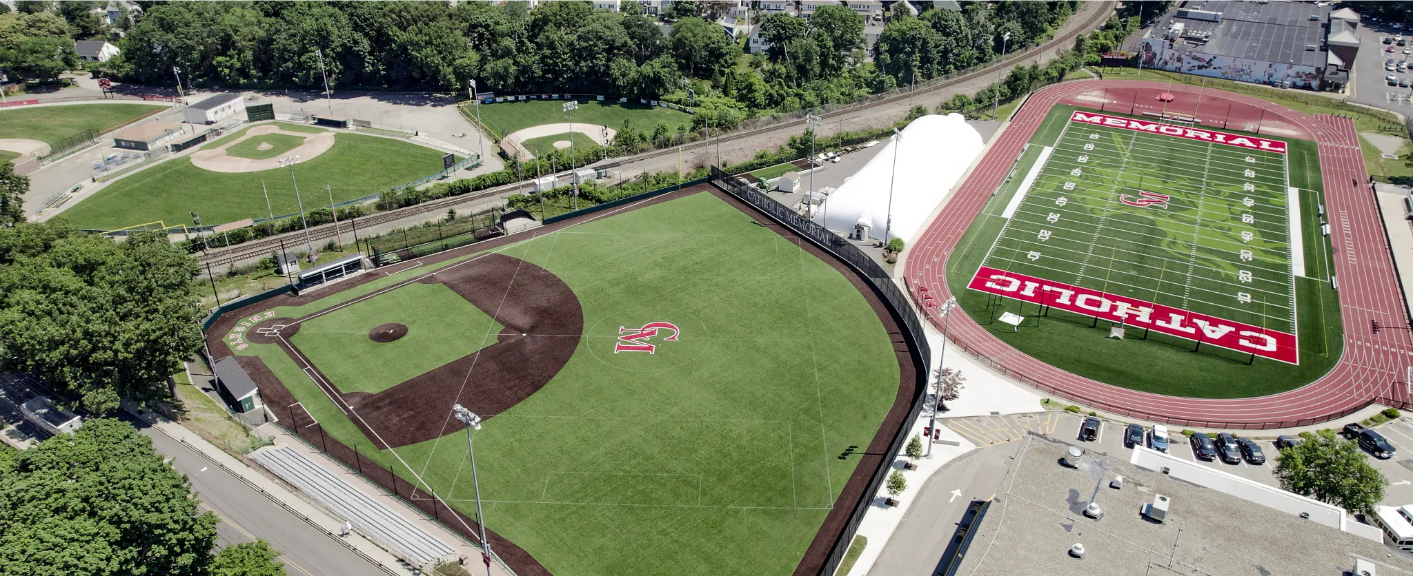 Aerial view of sports complex featuring artificial turf baseball and football fields