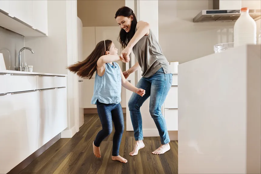 Coretec Residential WPC Luxury Vinyl Plank Flooring in Modern Kitchen - 48.03x7.05 inch kitchen with luxury vinyl plank floor in a wood look with a young woman and child dancing dimensions 4803x705 inch