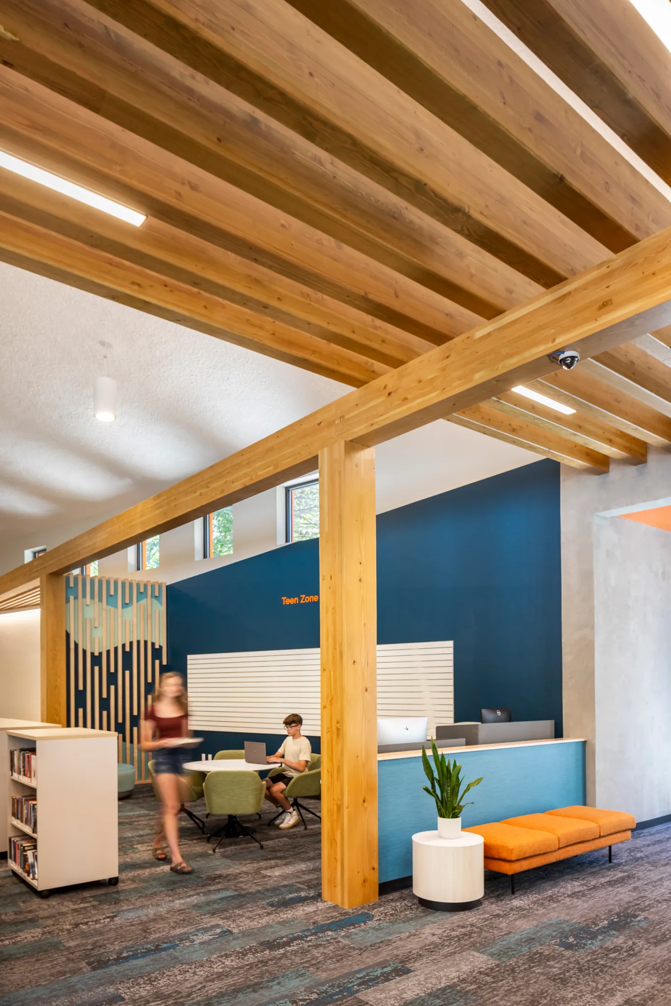 Modern education facility with exposed wooden beams and commercial carpet tile flooring in shades of blue and gray