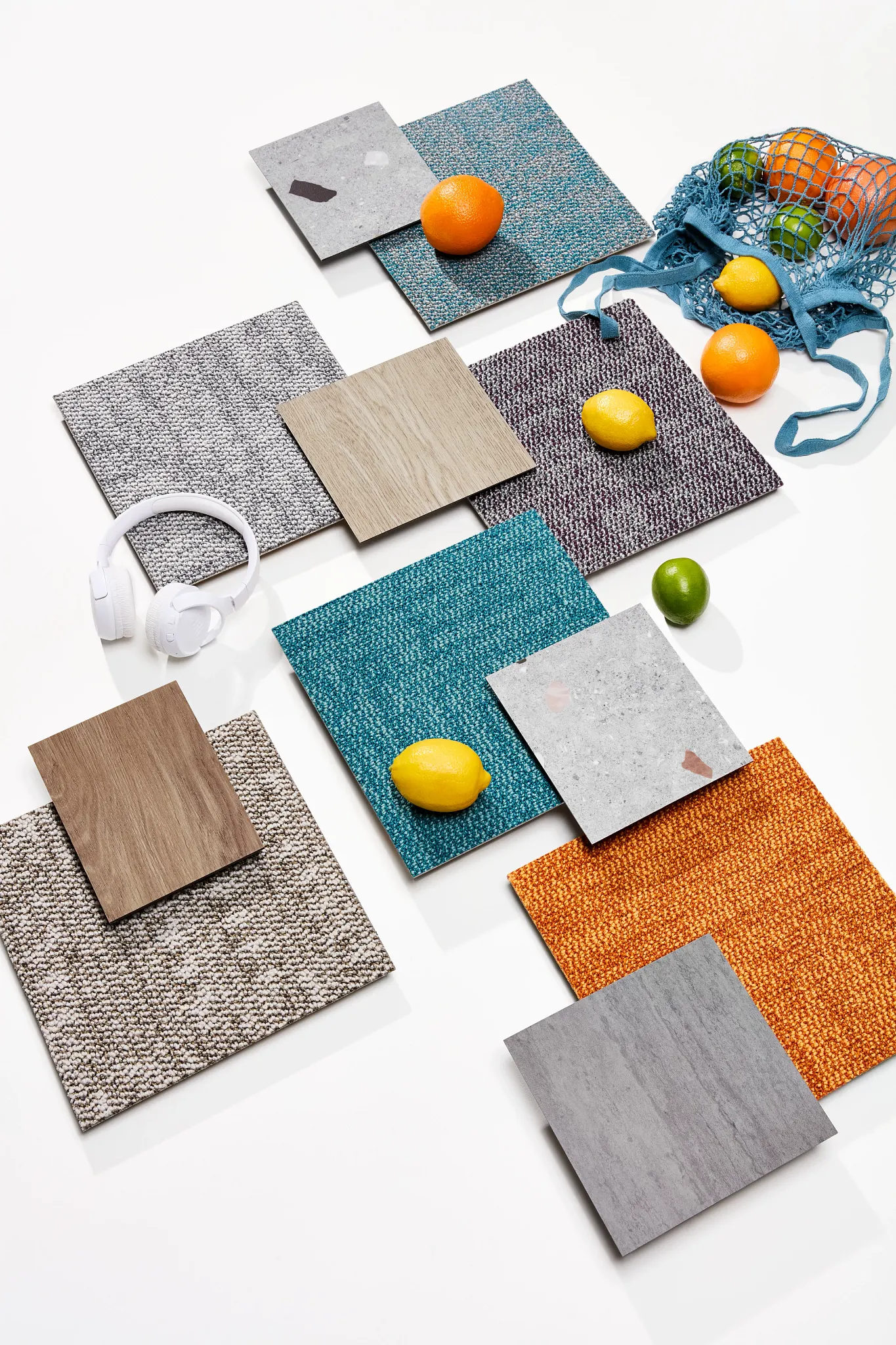 Assorted flooring swatches in gray, teal, orange, and wood tones with citrus fruits