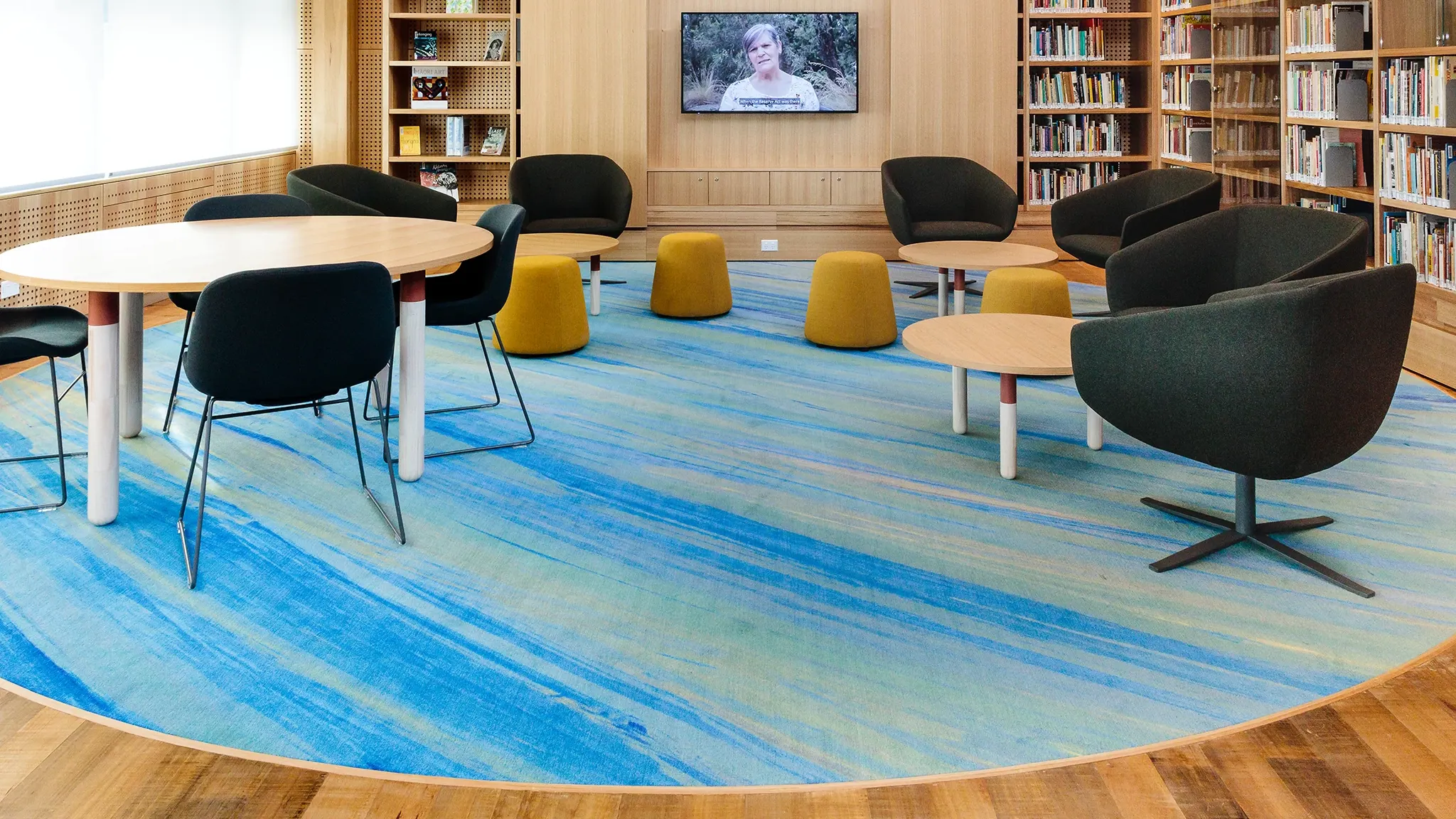 Area in library with sky blue rug and tables and chairs