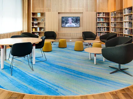 Education Facility with Blue and Green Commercial Carpet Tile in Library Setting Modern library setting with blue and green commercial carpet tile, featuring round tables and black chairs