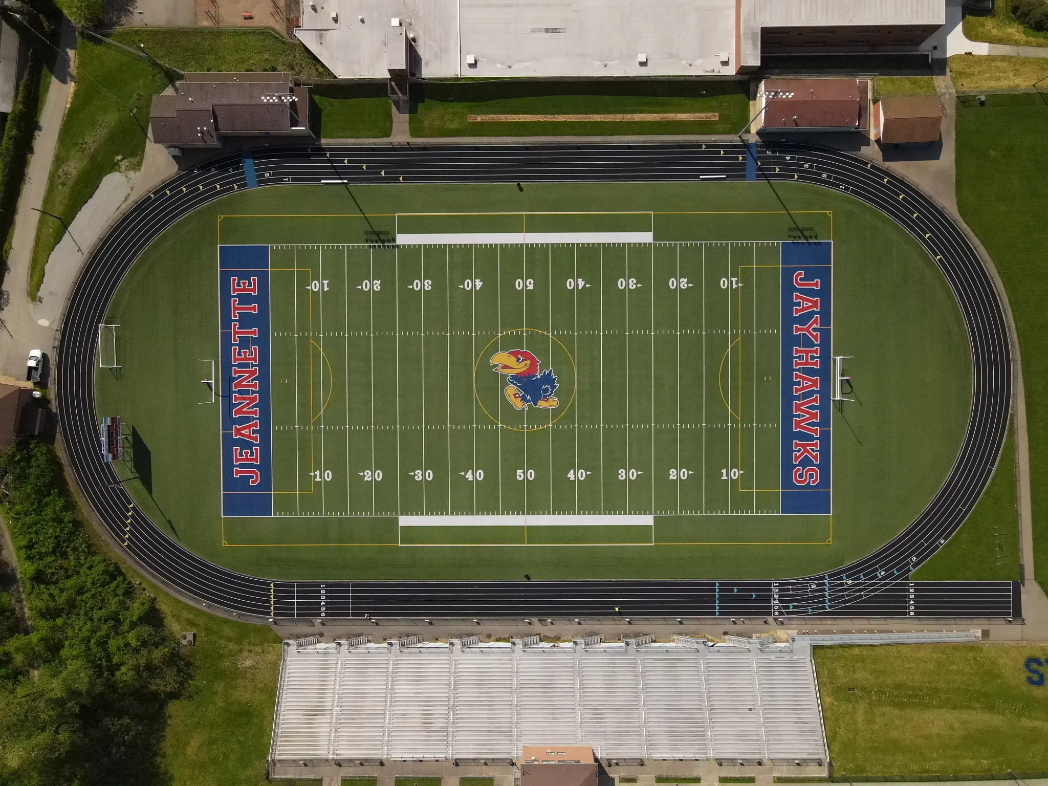 Aerial view of a football field with track and surrounding buildings