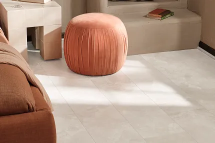 Coretec Mineral Core Residential LVT Flooring - Stone Look, 23.62x11.81 inch Cozy living room with Coretec Mineral Core Residential luxury vinyl tile flooring in a stone look, featuring a soft peach ottoman and a modern side table with decor