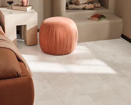 Coretec Mineral Core Residential LVT Flooring - Stone Look, 23.62x11.81 inch Cozy living room with Coretec Mineral Core Residential luxury vinyl tile flooring in a stone look, featuring a soft peach ottoman and a modern side table with decor