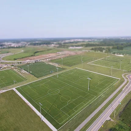Artificial Turf Sports Fields Aerial View Aerial view of multiple sports fields with artificial turf surrounded by roads and greenery