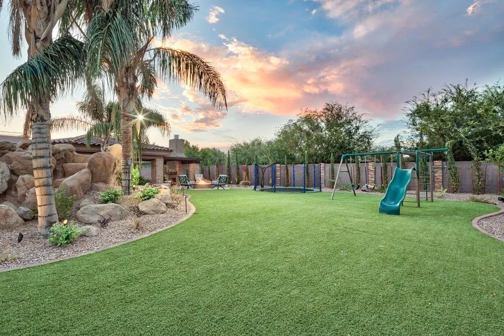 Backyard with artificial grass and playground at sunset