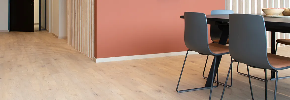 Light wood flooring in a modern dining area with coral accent wall