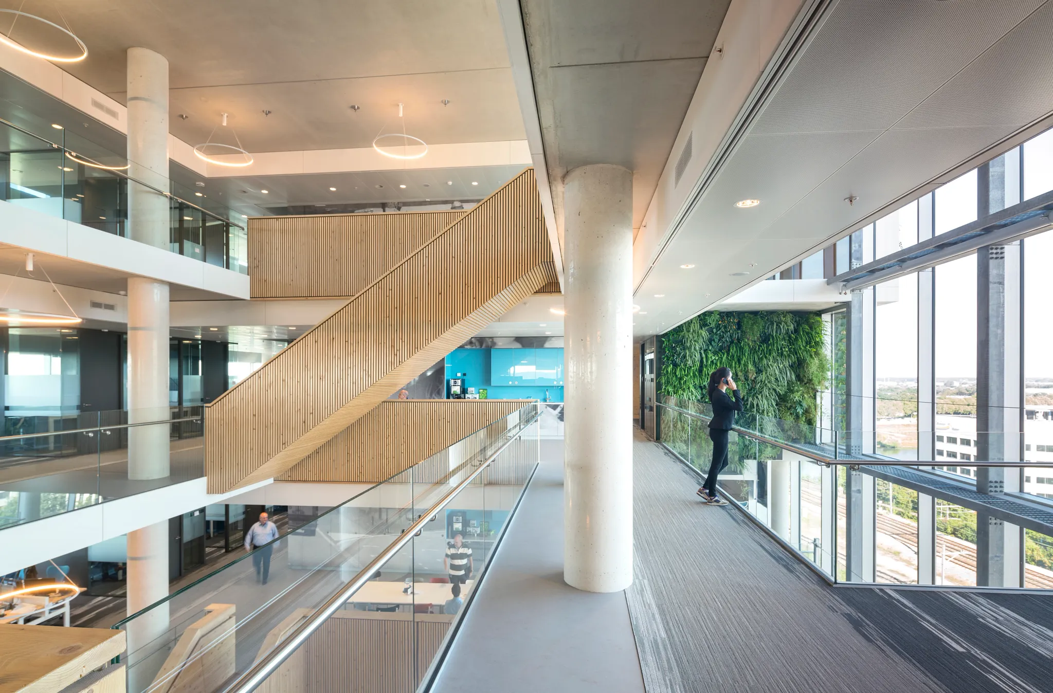 Modern workplace interior with open staircases, glass railings, and large windows
