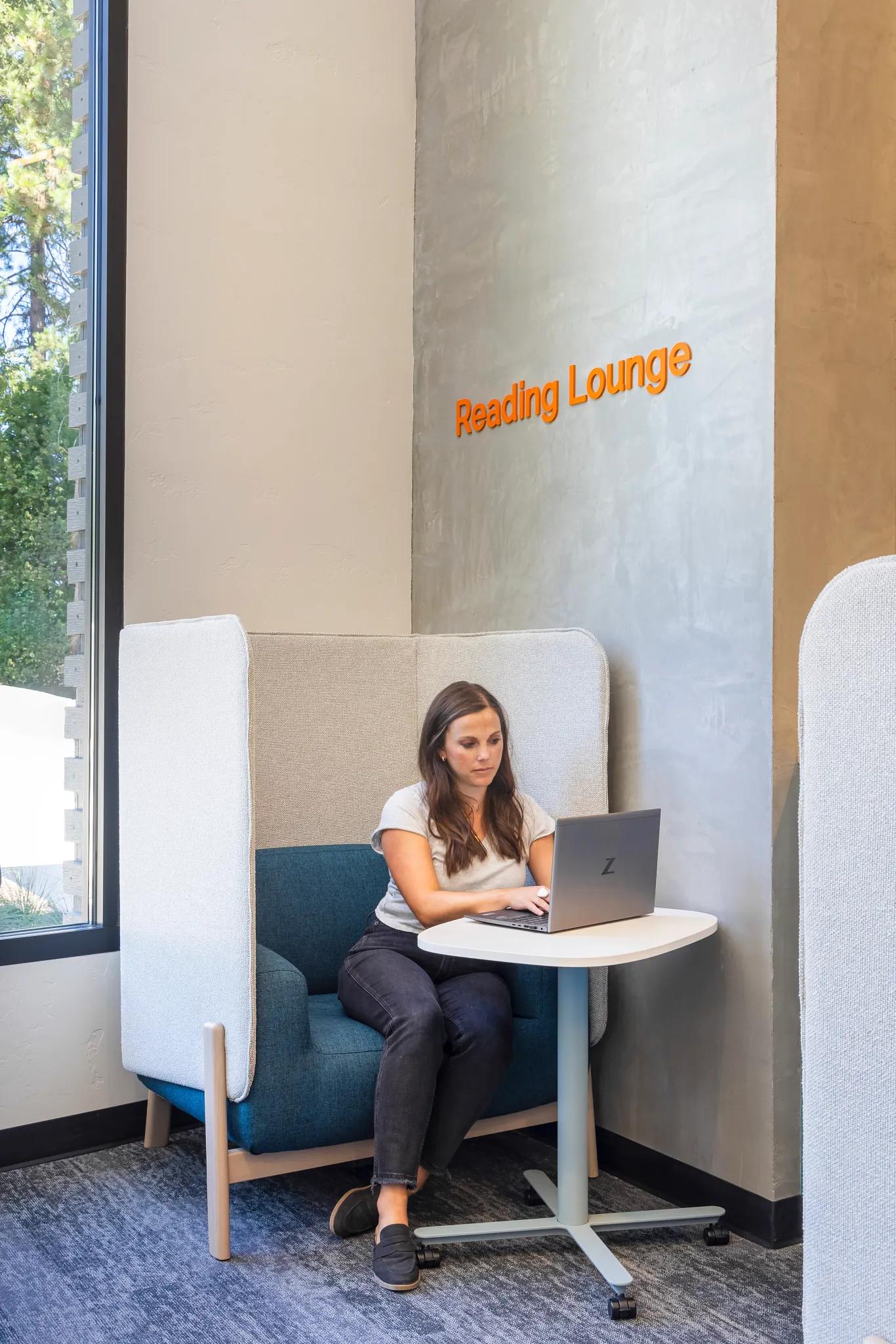 Woman working on a laptop in a reading lounge with commercial carpet tile flooring, 9x36 inch, Education Facility