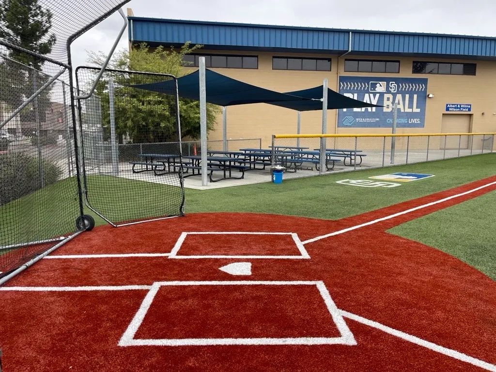 Baseball field with red and green turf near a community building