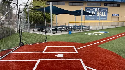 Durable sports turf for baseball fields Baseball field with red and green turf near a community building