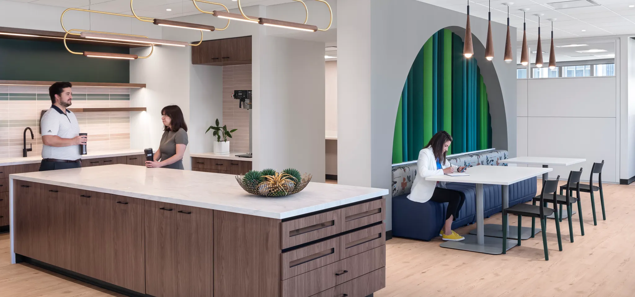 Modern workplace kitchen with light wood flooring and contemporary furniture