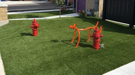 Modern outdoor space with synthetic turf and art installation Artificial grass lawn with red hydrant and sculpture