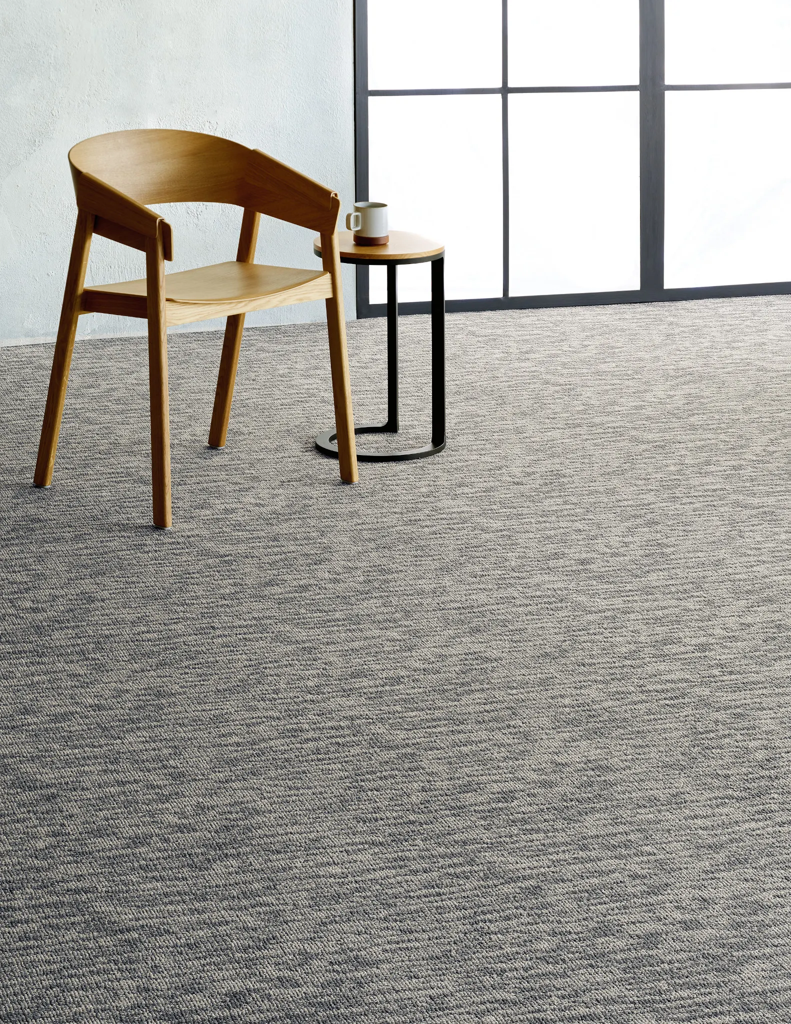 Modern room with light wood chair and small table on gray commercial carpet tile