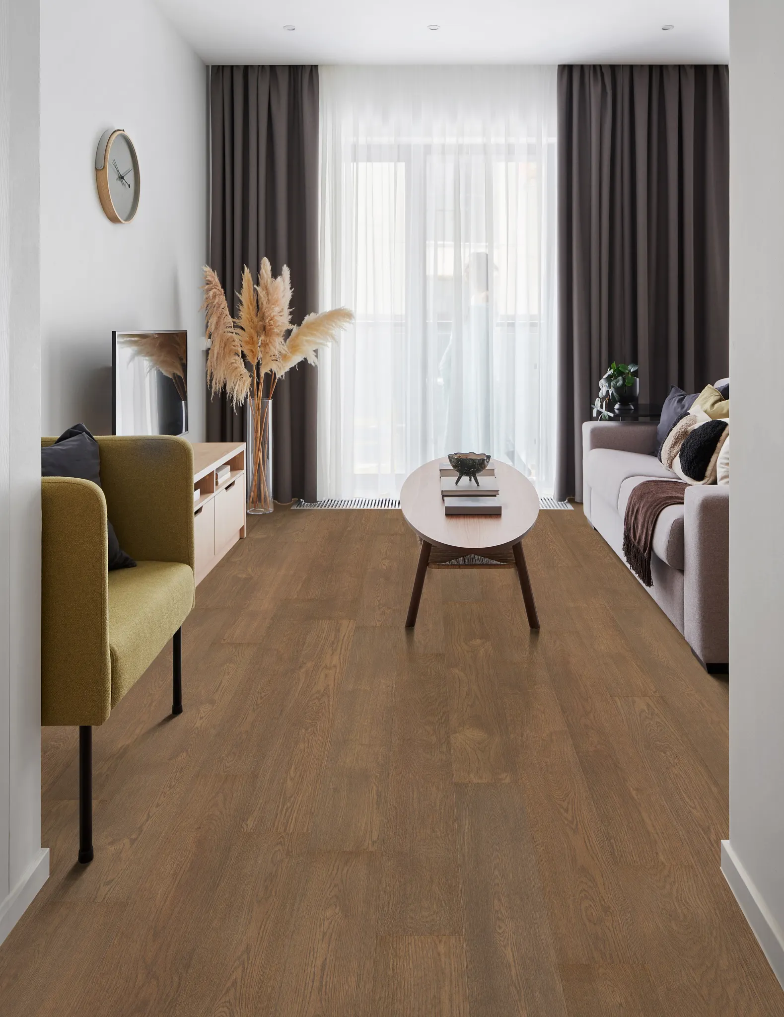 Modern living room with brown wood-look flooring, featuring a beige armchair, a light wood coffee table, and a gray sofa with decorative pillows