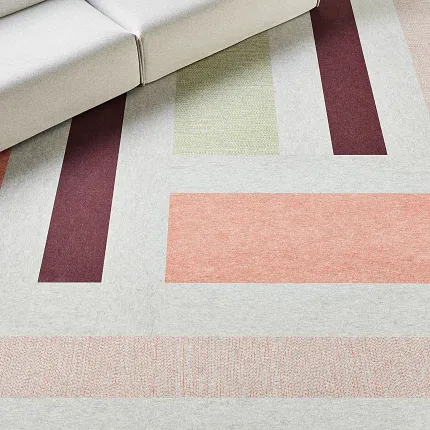 Geometric Pattern Carpet in Modern Living Room with Light Grey Sofa Modern living room with geometric pattern carpet in shades of grey, peach, burgundy, and green, featuring a light grey sofa with a coral cushion