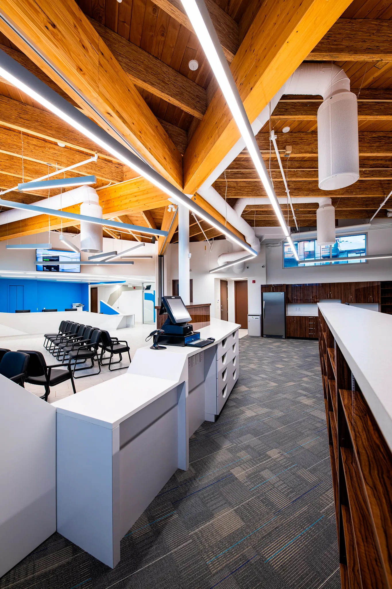 Modern retail facility with commercial carpet tile flooring, featuring a spacious layout with wooden ceiling beams and contemporary furniture.